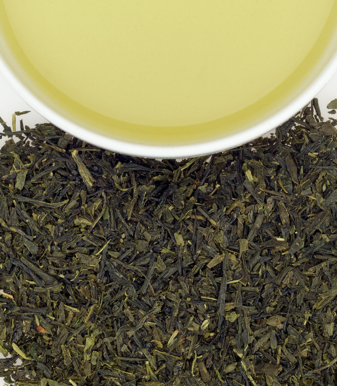 Freshly brewed Bancha green tea in a white cup, surrounded by loose Bancha tea leaves.