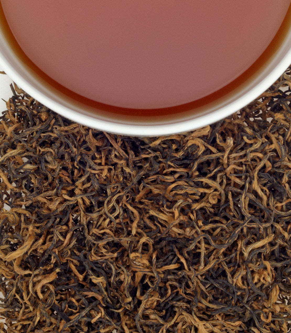 Close-up of Black King tea leaves with a cup of brewed tea, showcasing rich colors and textures.