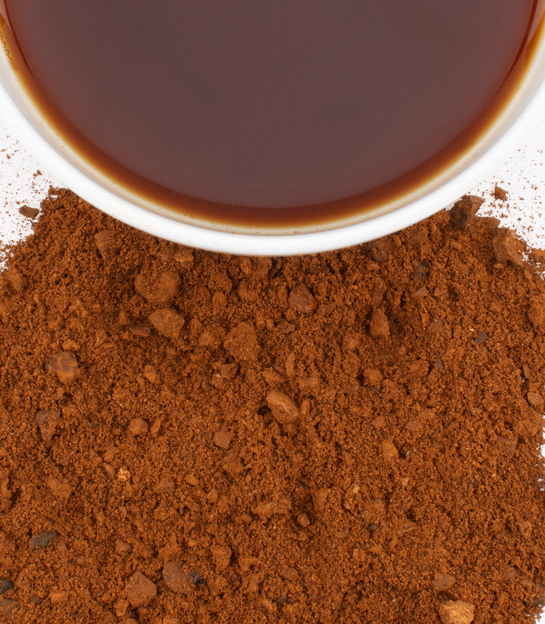 Chaga mushroom powder with brewed tea in a cup, showcasing a rich brown color and fine texture.