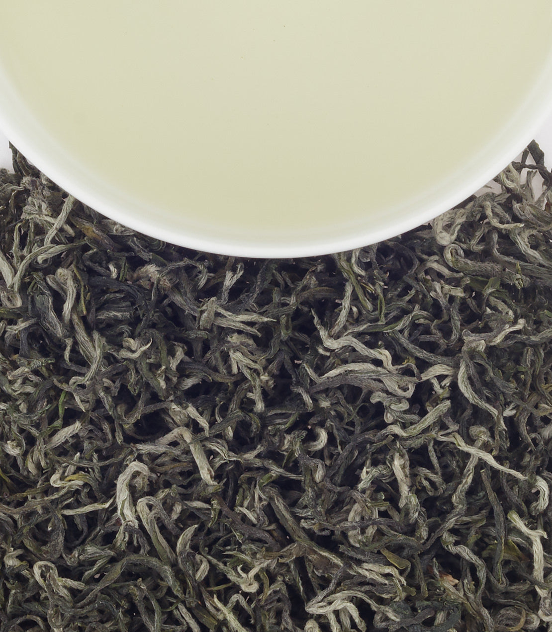 Freshly brewed Green Gulou tea with delicate leaves, showcasing a light yellow-green hue in a white cup.