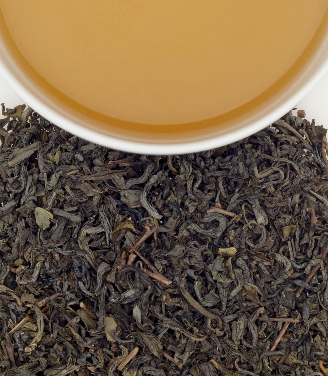 Organic Chun Mee tea leaves with brewed tea in a white cup, showcasing rich color and texture.