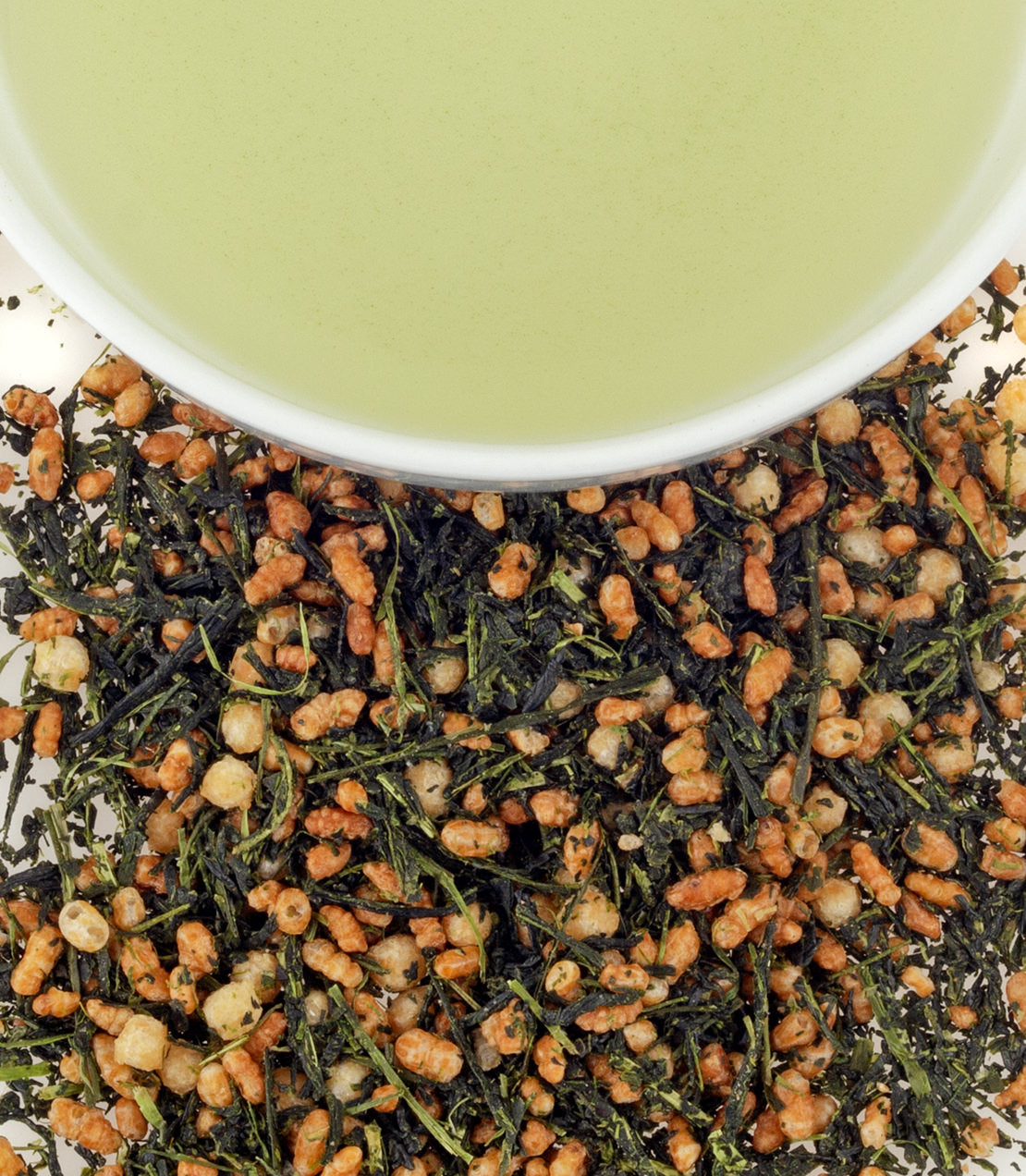 A bowl of green tea above a pile of Duck Rice Genmaicha, featuring toasted rice and green tea leaves.