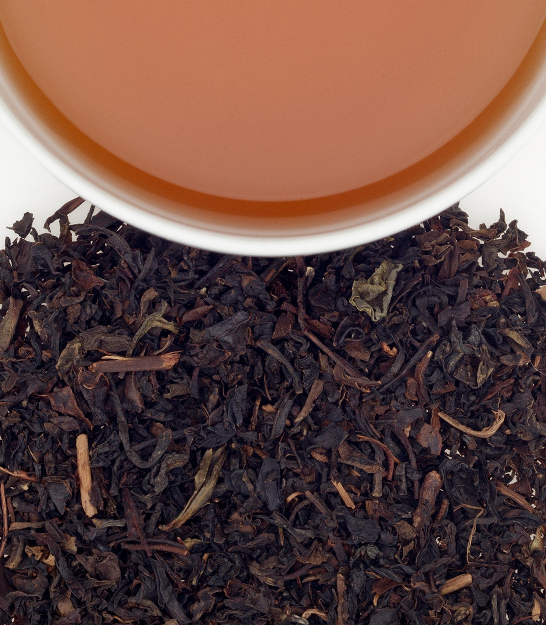 A close-up of Formosa Oolong tea leaves with a cup of brewed tea above, showcasing rich colors and textures.