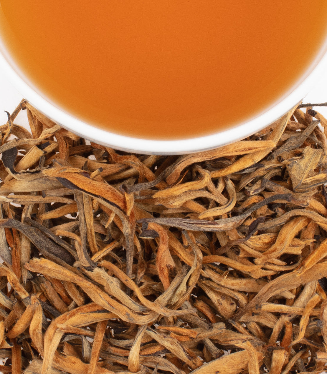 Golden Yinzhen tea leaves with a cup of brewed tea above, showcasing rich amber color and delicate, twisted leaves.