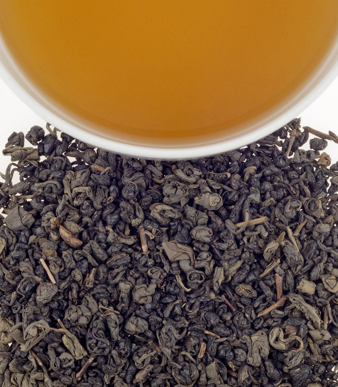 Organic Gunpowder tea leaves with a cup of brewed tea above, showcasing rich color and texture.