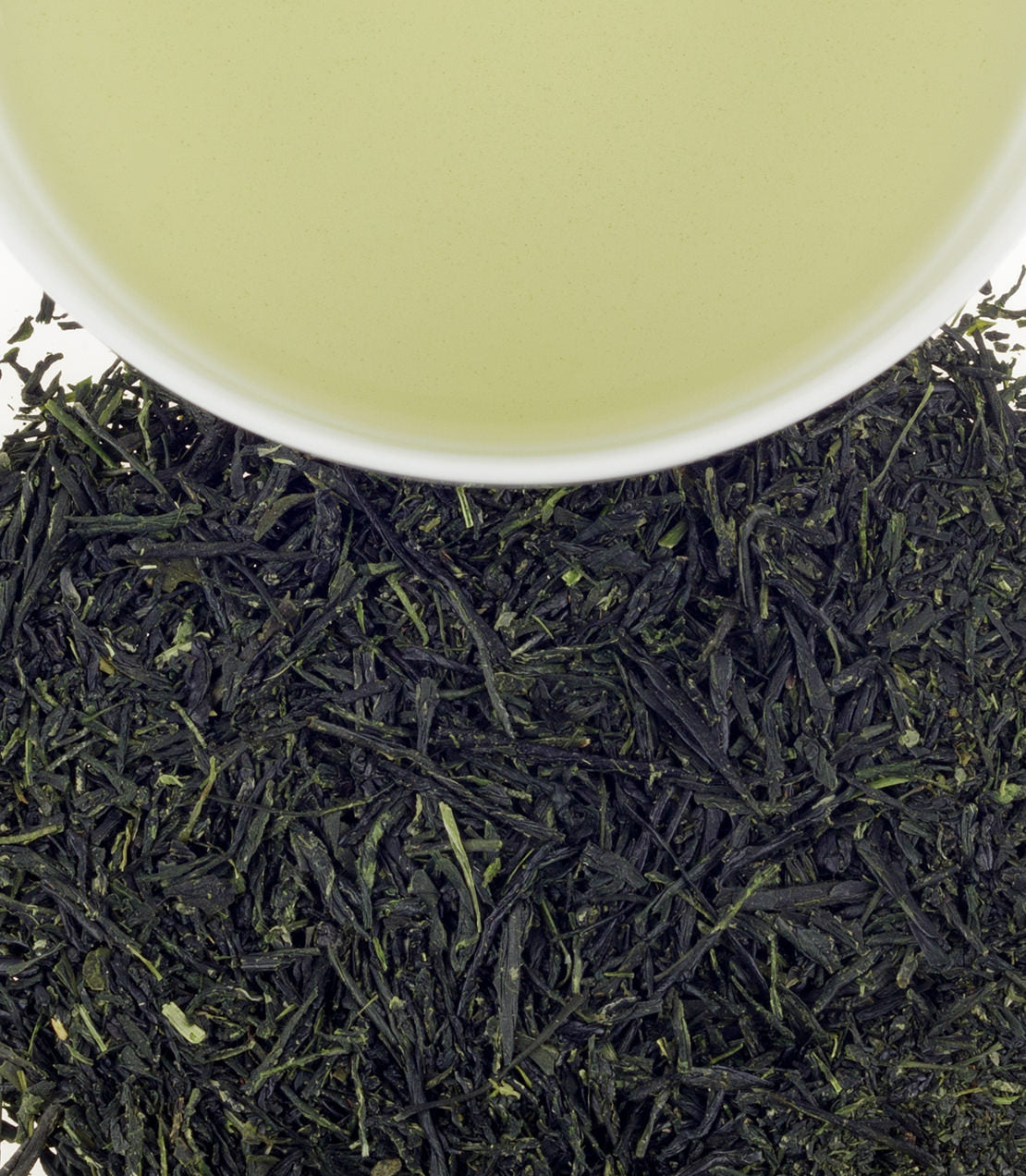 Gyokuro green tea leaves with a cup of brewed tea above, showcasing vibrant green color and rich texture.