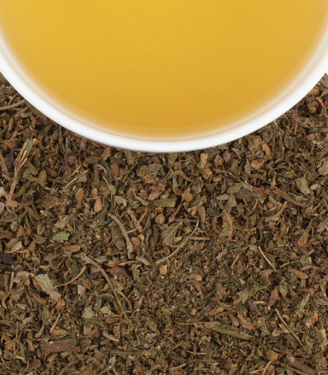 Close-up of dried hemp leaves with a cup of hemp tea, showcasing earthy tones and natural textures.
