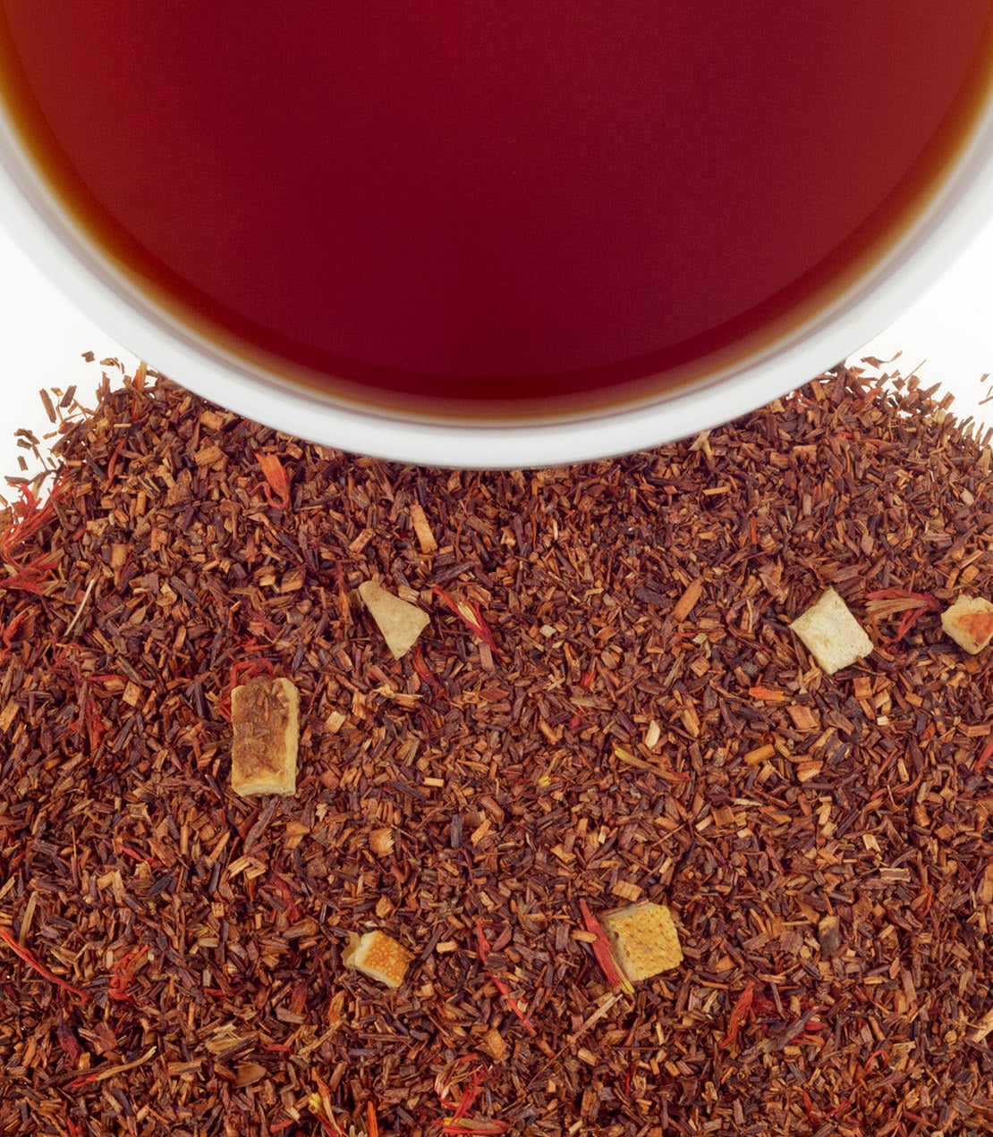 A close-up of loose herbal tea blend with dried ingredients, next to a cup of brewed tea.