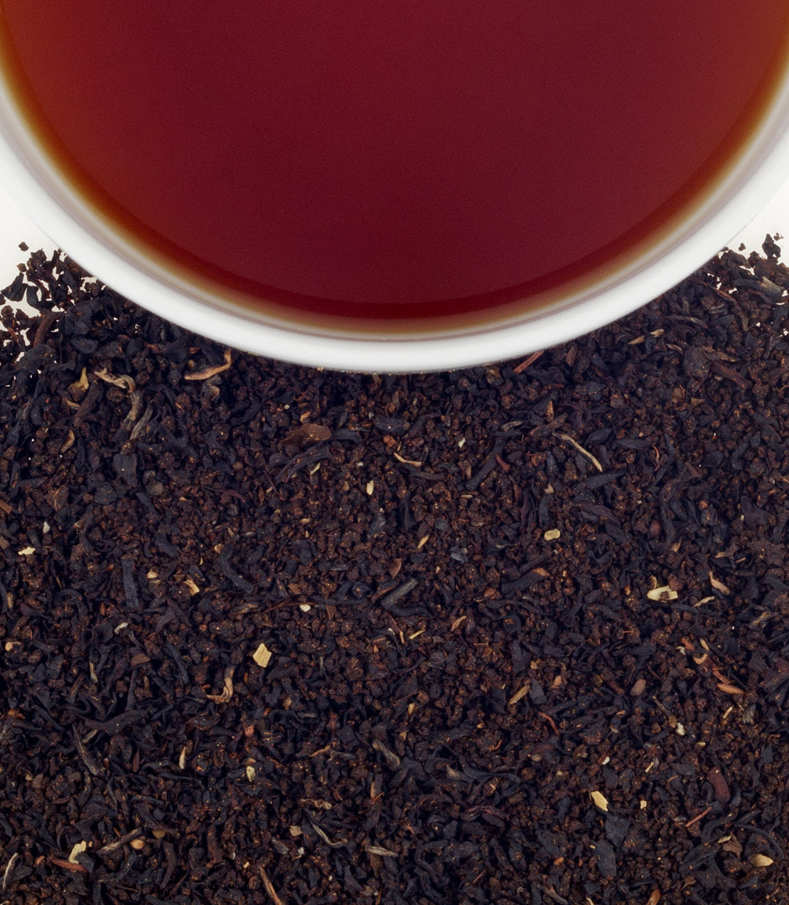 A close-up of loose Indian spice tea leaves with a cup of brewed tea above, showcasing rich colors and textures.