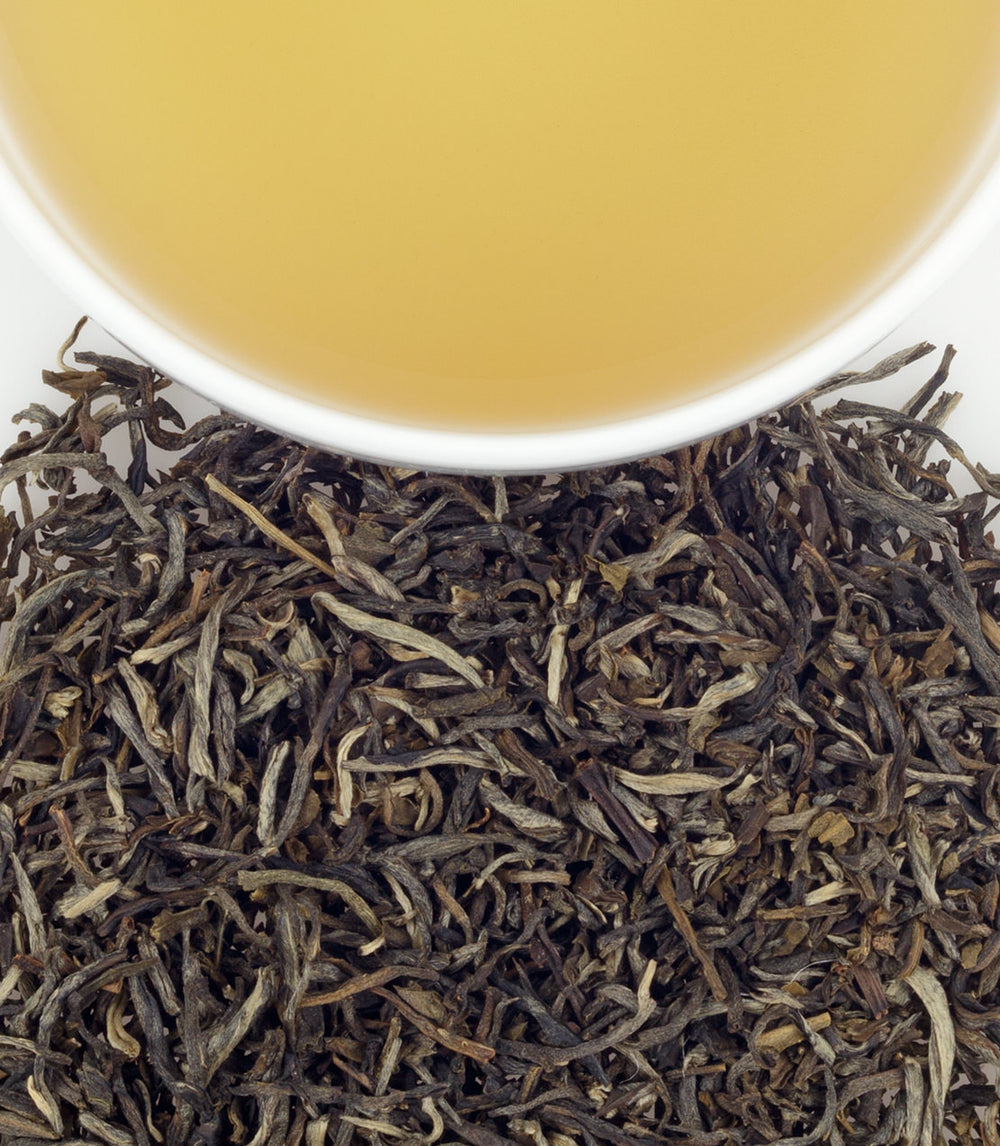 Jasmine tea sachets in a bag of 50, with brewed tea in a cup above loose tea leaves.