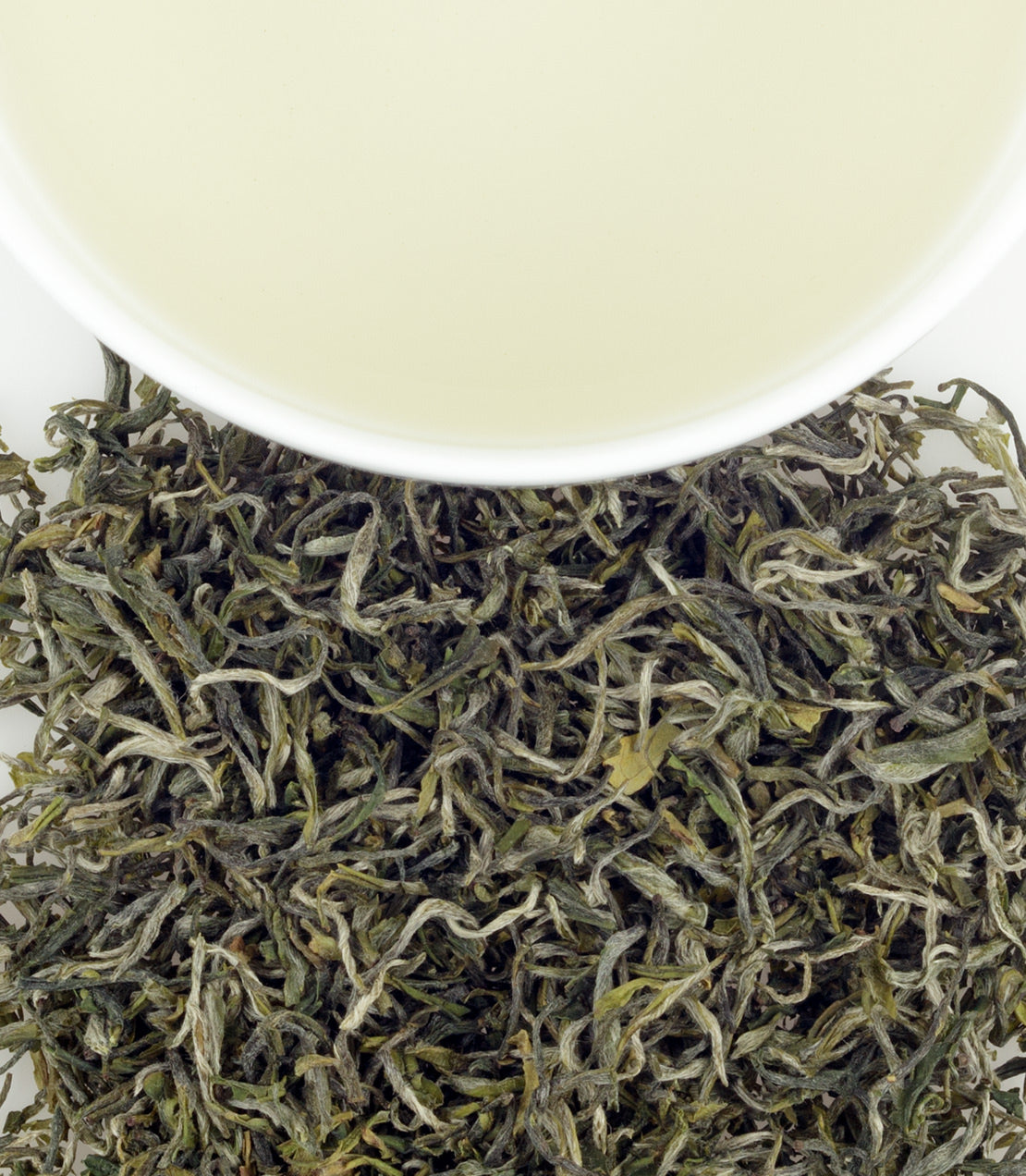 Jin Shan tea leaves with a cup of brewed tea above, showcasing the delicate green color and texture.