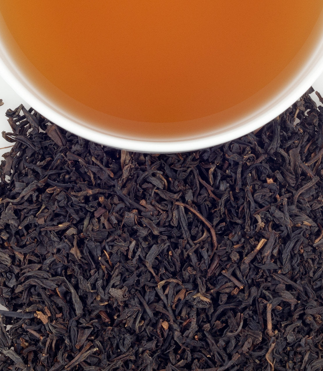 Lapsang Souchong tea sachets with brewed tea in a cup, showcasing dark, twisted tea leaves.