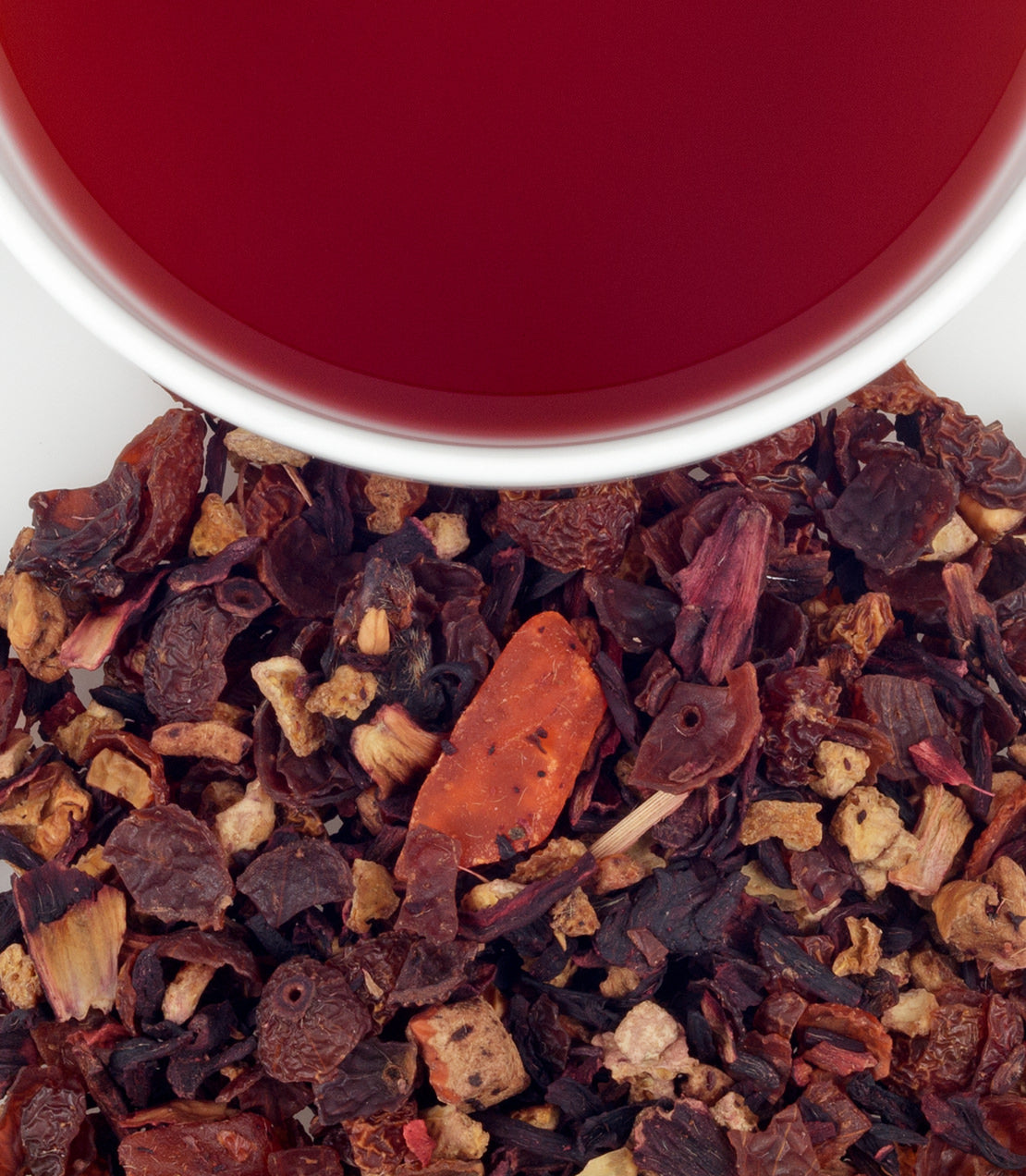 A vibrant cup of mango fruit tea beside dried fruit tea blend, showcasing rich colors and textures.