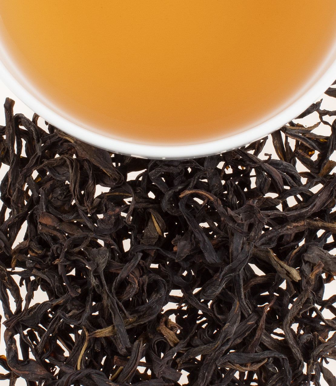 A close-up of Mi Lan Xiang Dan Con tea leaves with a cup of brewed tea, showcasing rich colors and textures.