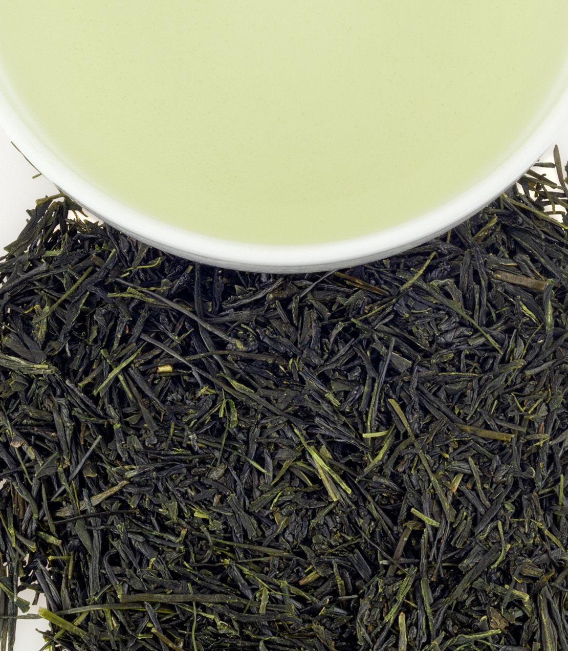 Fresh green tea leaves surround a cup of vibrant green tea, showcasing the essence of Mist of Kawane.