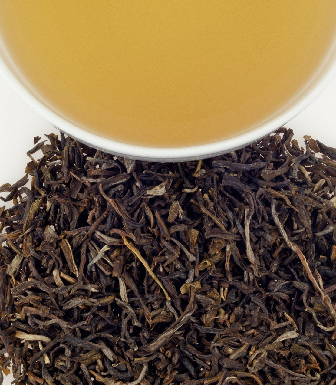Organic jasmine tea leaves with a cup of brewed tea above, showcasing rich colors and textures.