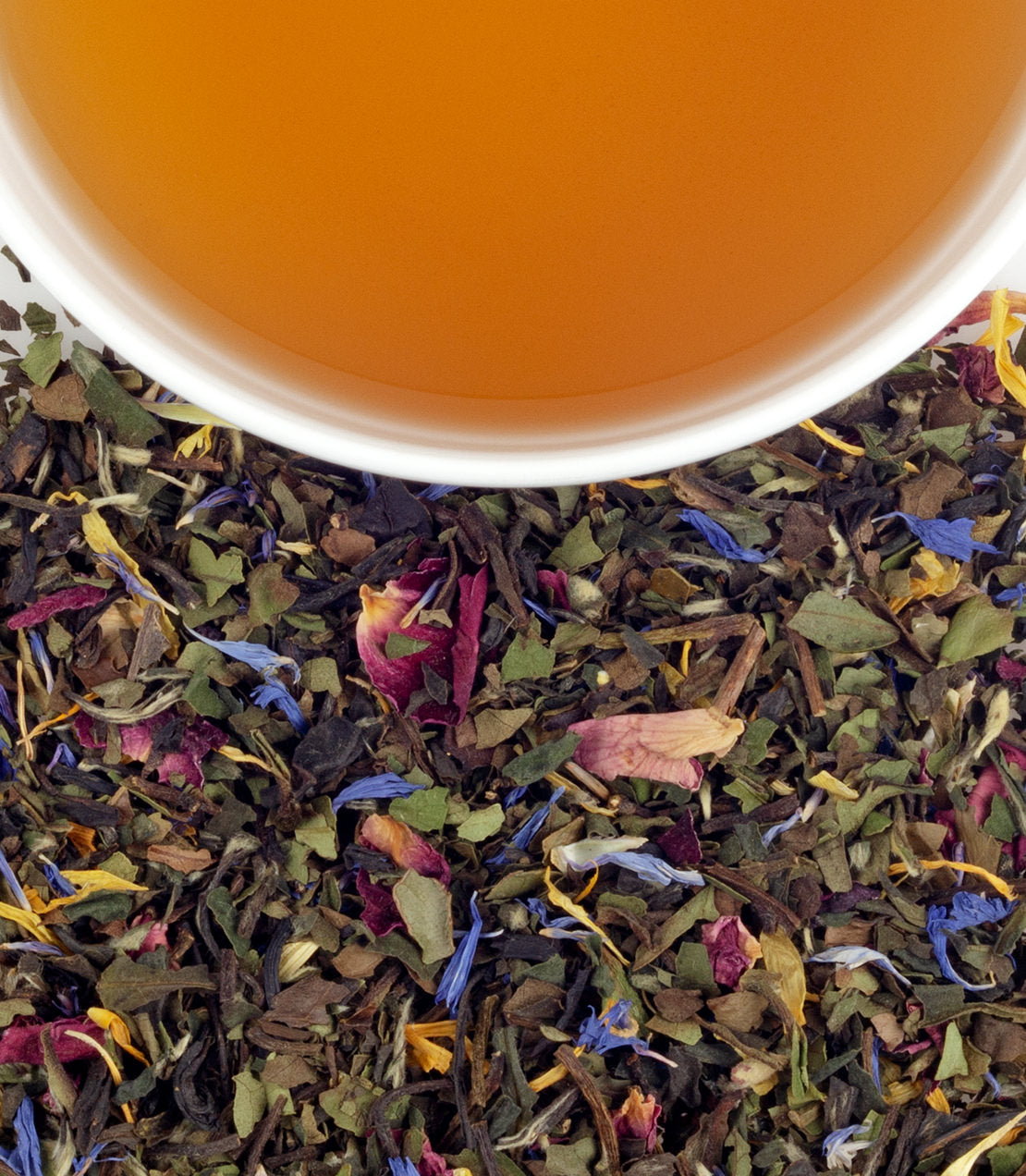 A close-up of Royal Wedding Tea, featuring a cup of brewed tea above a blend of colorful dried herbs and flowers.