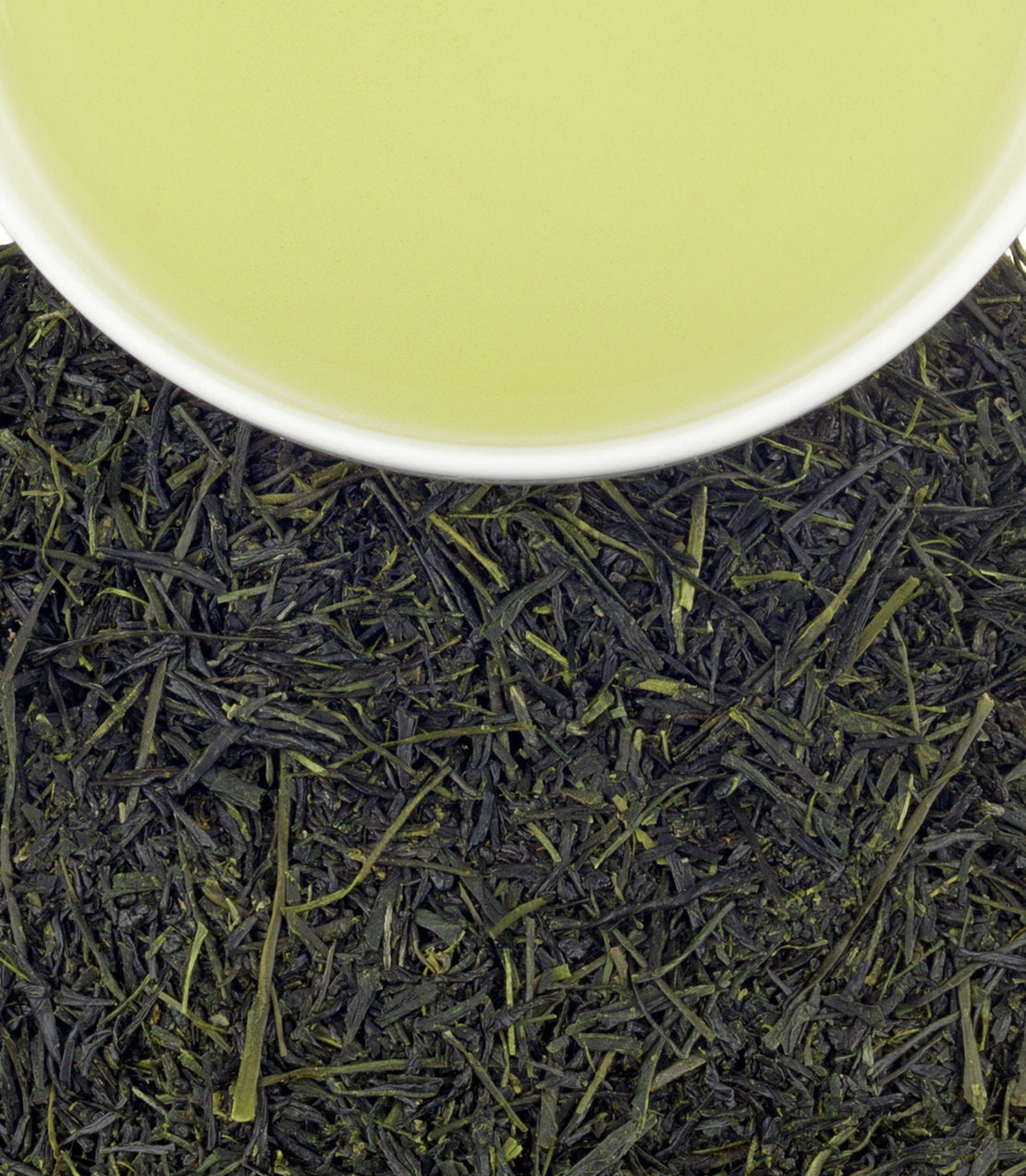 A cup of light green Sencha tea above a bed of dark green tea leaves, showcasing its fresh aroma and quality.