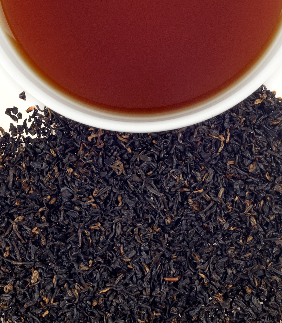 A close-up of Songluo Broken black tea leaves with a cup of brewed tea above, showcasing rich color and texture.