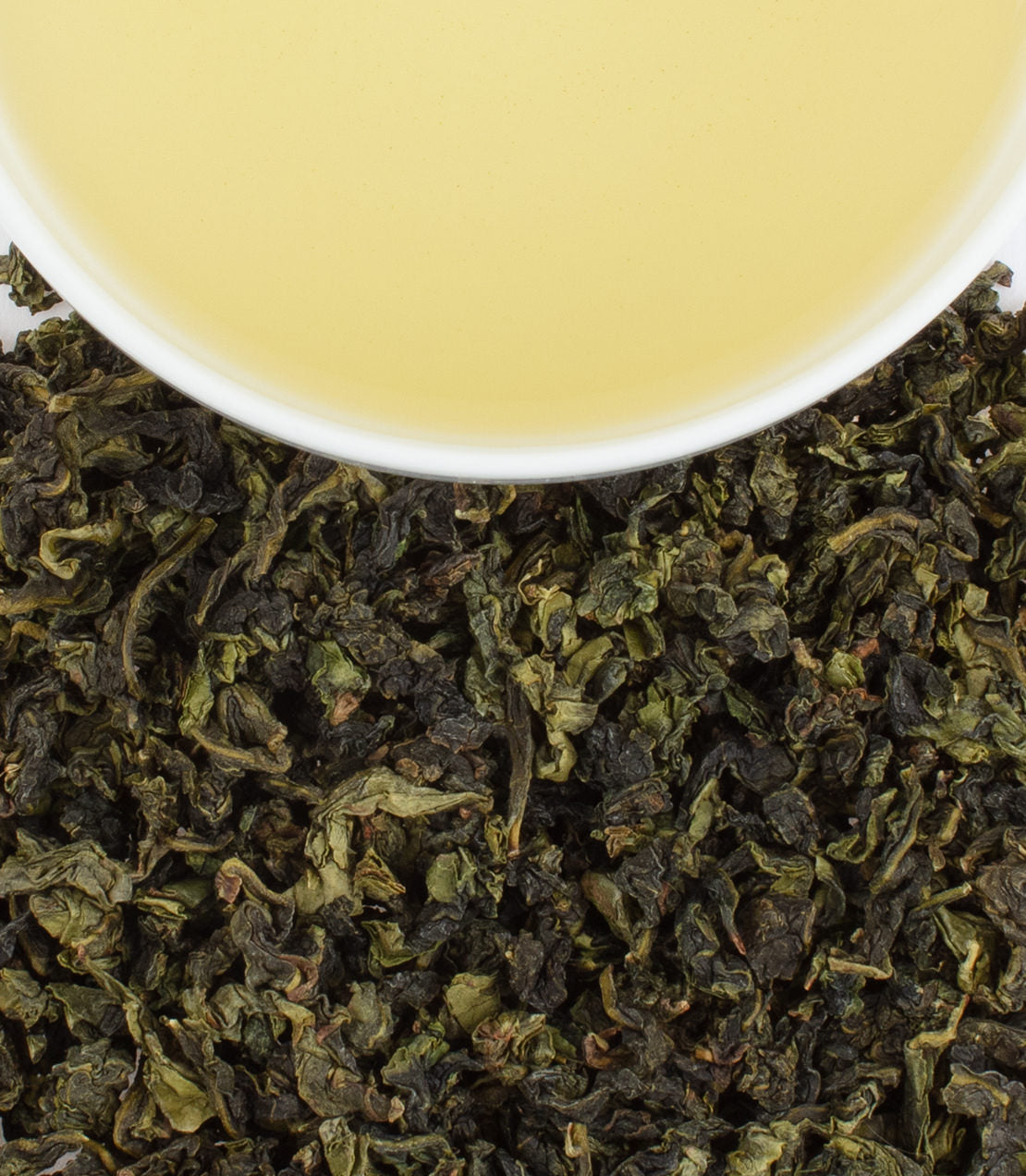 Top Ti Quan Yin tea leaves with a cup of light yellow brewed tea above, showcasing the rich texture and color.