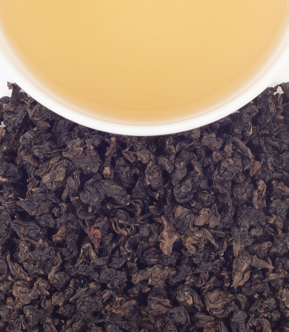 Traditional Ti Quan Yin tea leaves with a cup of brewed tea, showcasing rich color and texture.