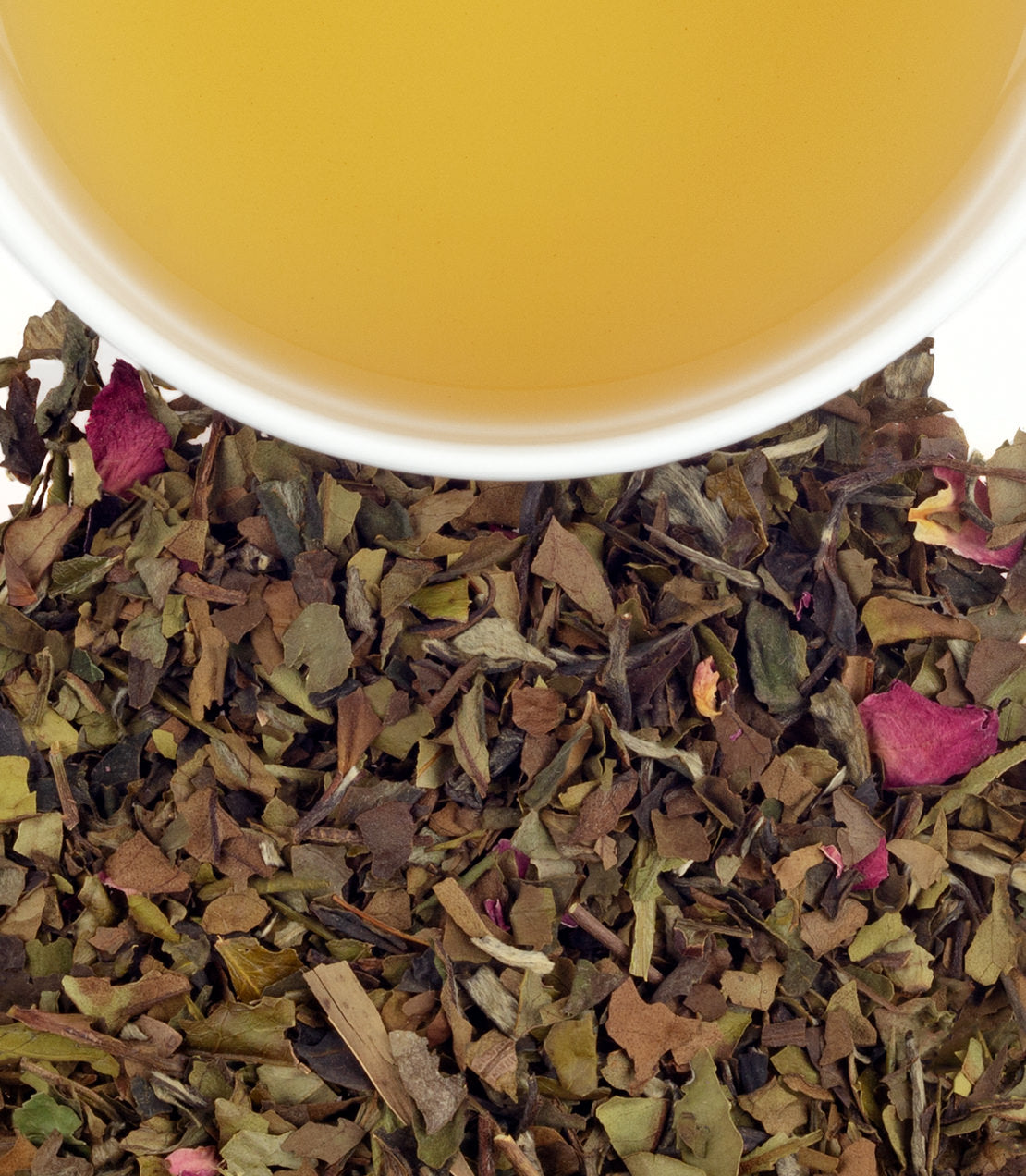 A cup of wedding tea above a blend of dried herbs and rose petals, showcasing its natural colors and textures.