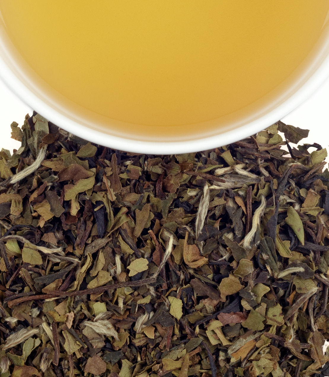 A cup of light yellow tea above a pile of dried white vanilla grapefruit tea leaves.
