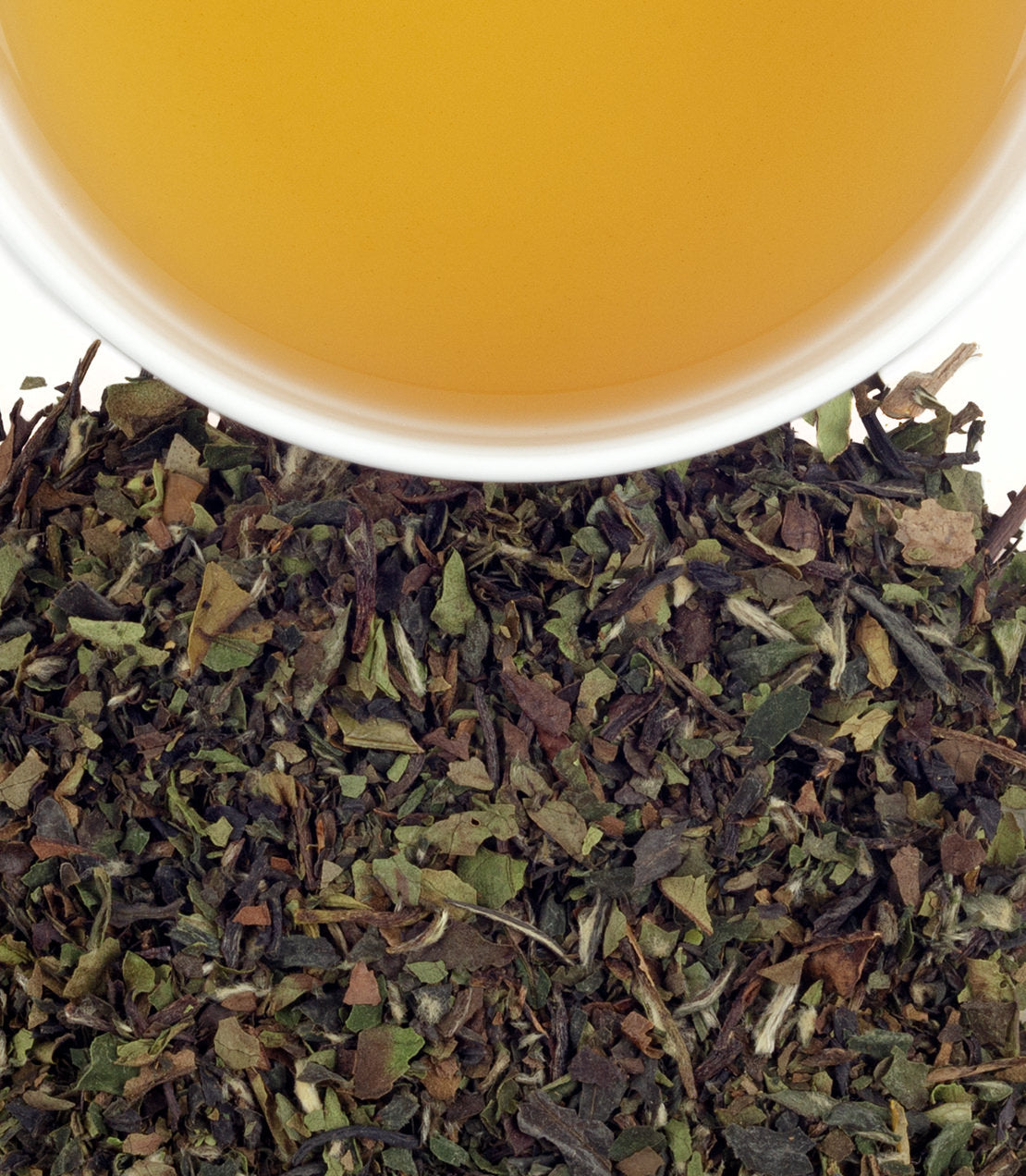 Winter White Earl Grey tea in a cup above loose tea leaves, showcasing its aromatic blend and color.