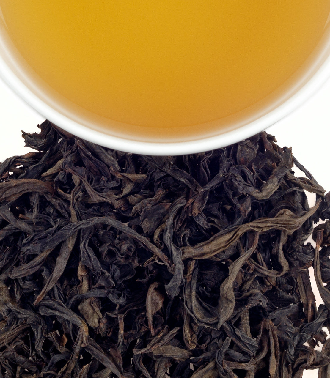 Wuyi Da Hong Pao tea leaves with brewed tea in a cup, showcasing rich color and texture.