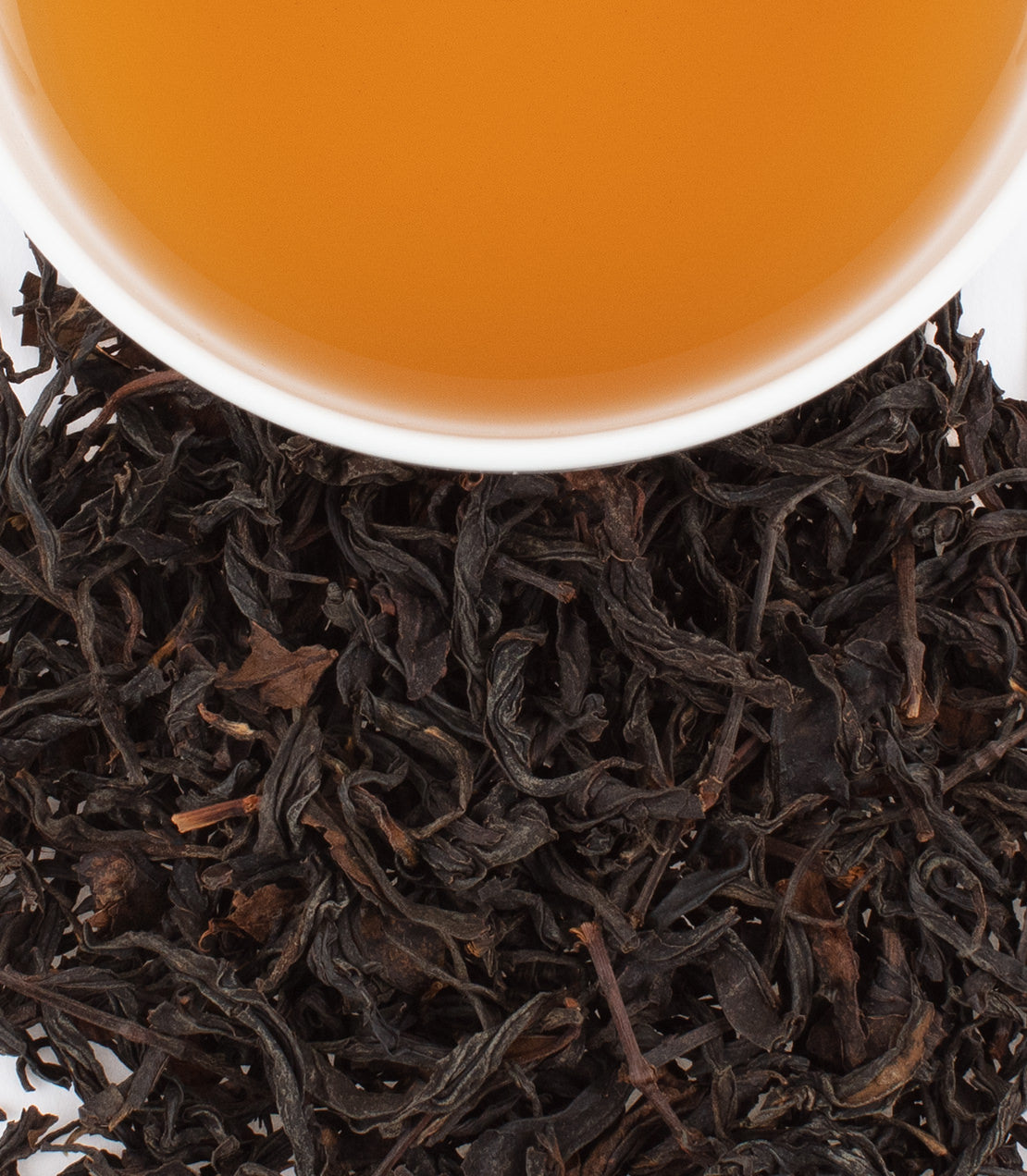 Wuyi Golden Beauty tea leaves with brewed tea in a white cup, showcasing rich color and texture.