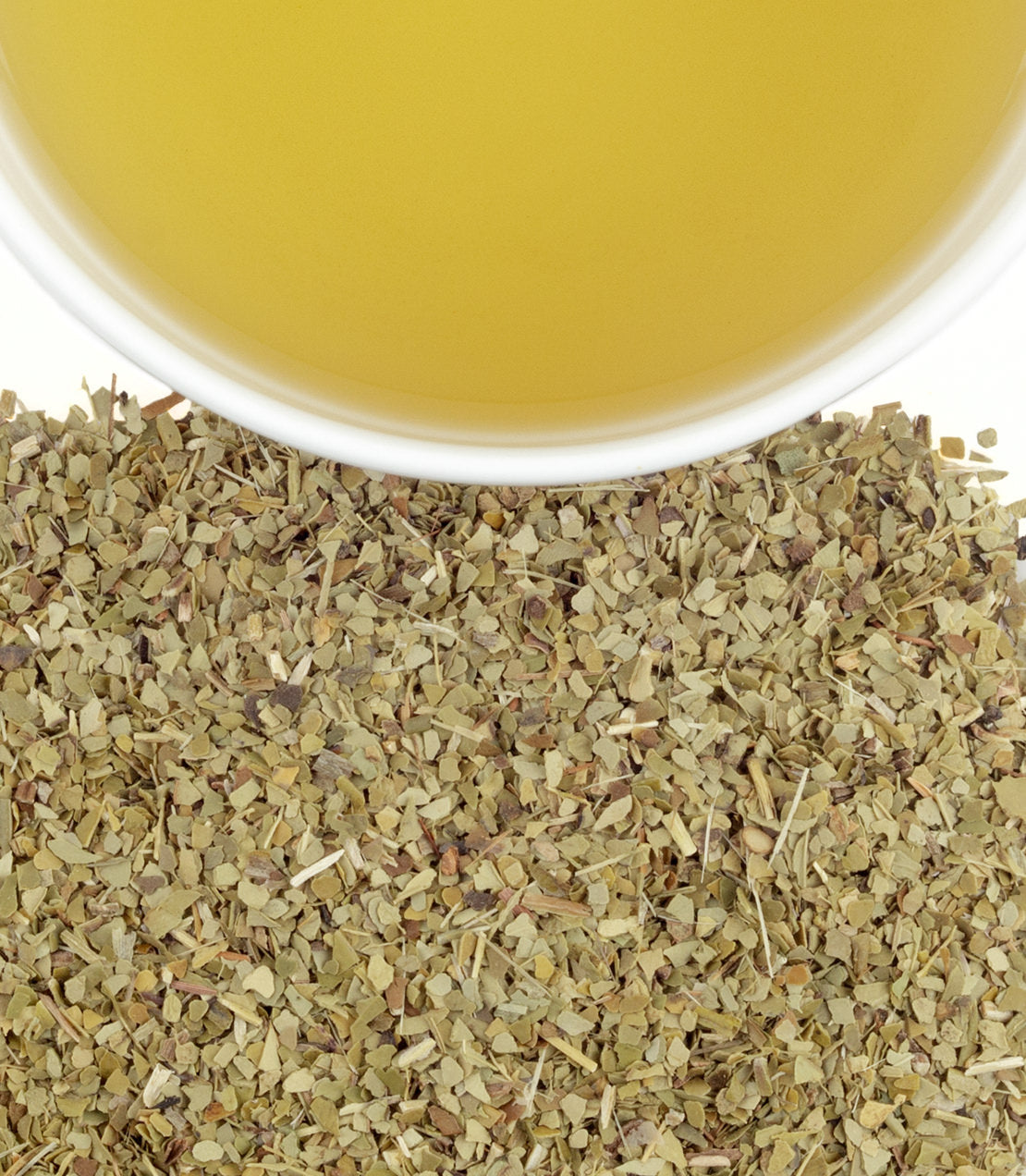 Yerba mate leaves beside a cup of brewed yerba mate tea, showcasing its vibrant green color.