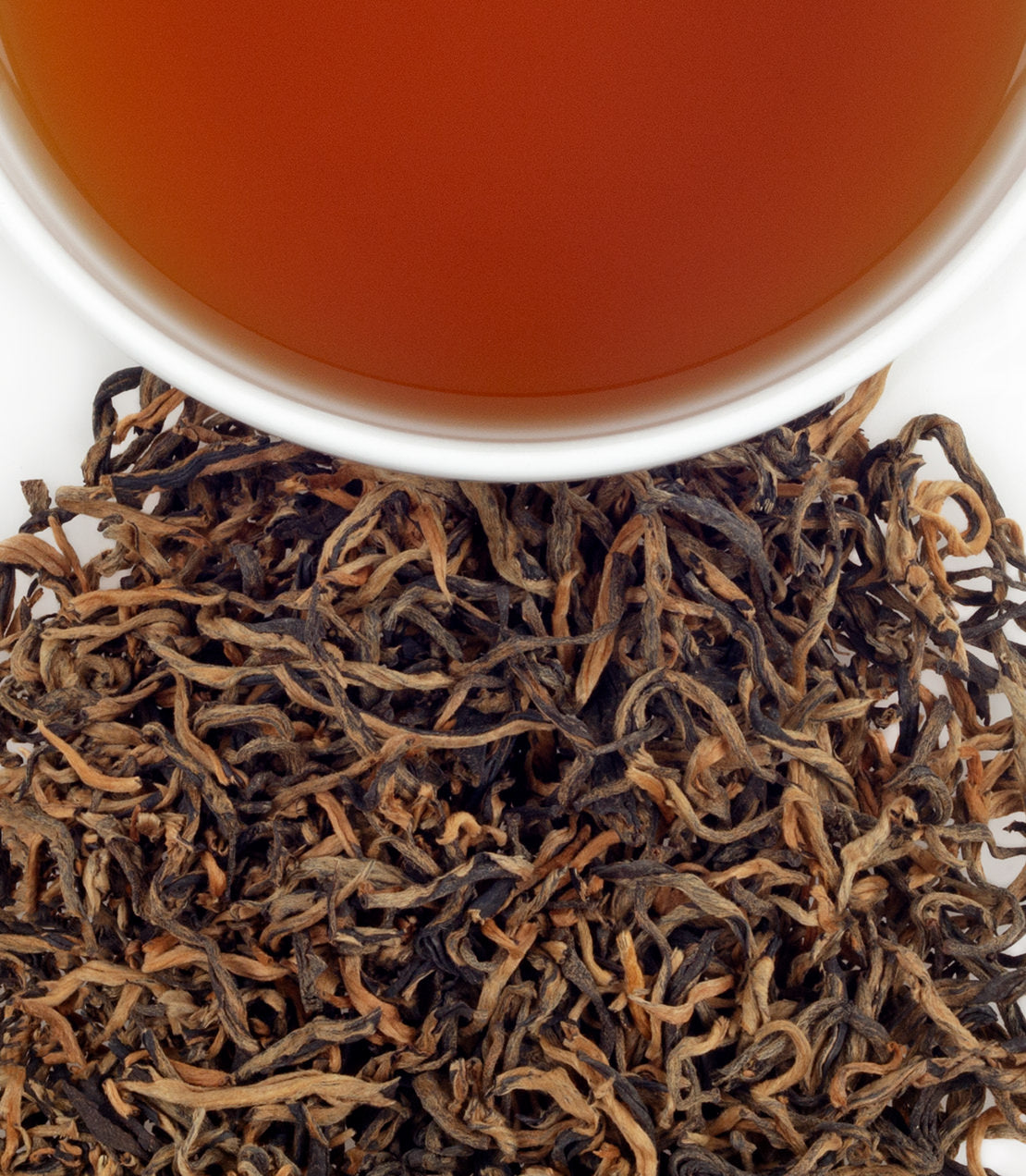 Yunnan Golden Tips tea leaves with brewed tea in a cup, showcasing rich color and texture.