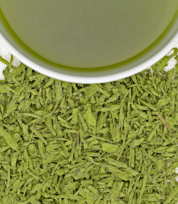 Close-up of white peach matcha powder beside a cup of vibrant green matcha tea.