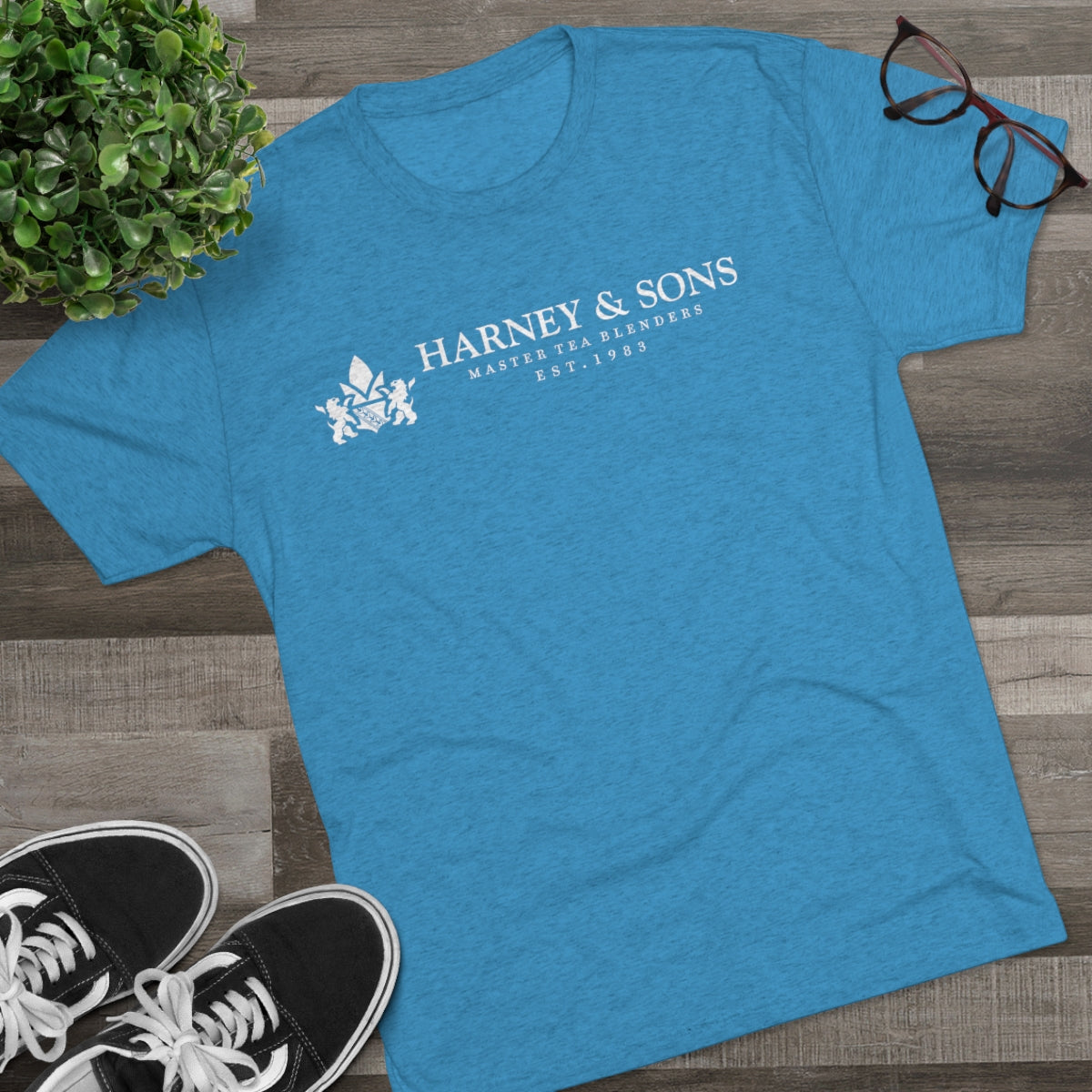 Blue graphic tee featuring "Harney & Sons Master Tea Blenders Est. 1983" text, paired with sneakers and glasses.