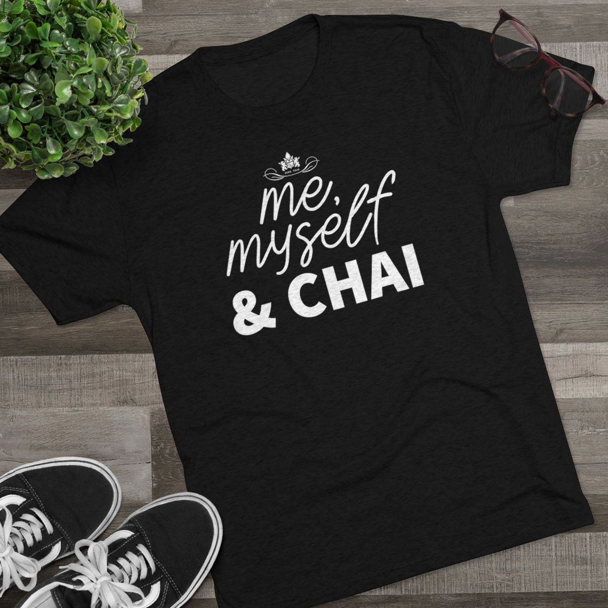 Black graphic tee featuring the text "me, myself & CHAI" in bold white letters, styled with casual sneakers and glasses.