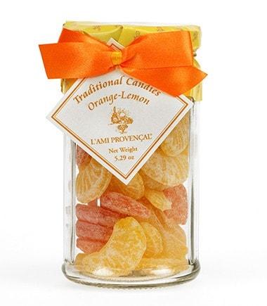 Glass jar filled with L'Ami Provençal traditional assorted candies in orange and lemon flavors, topped with an orange ribbon.