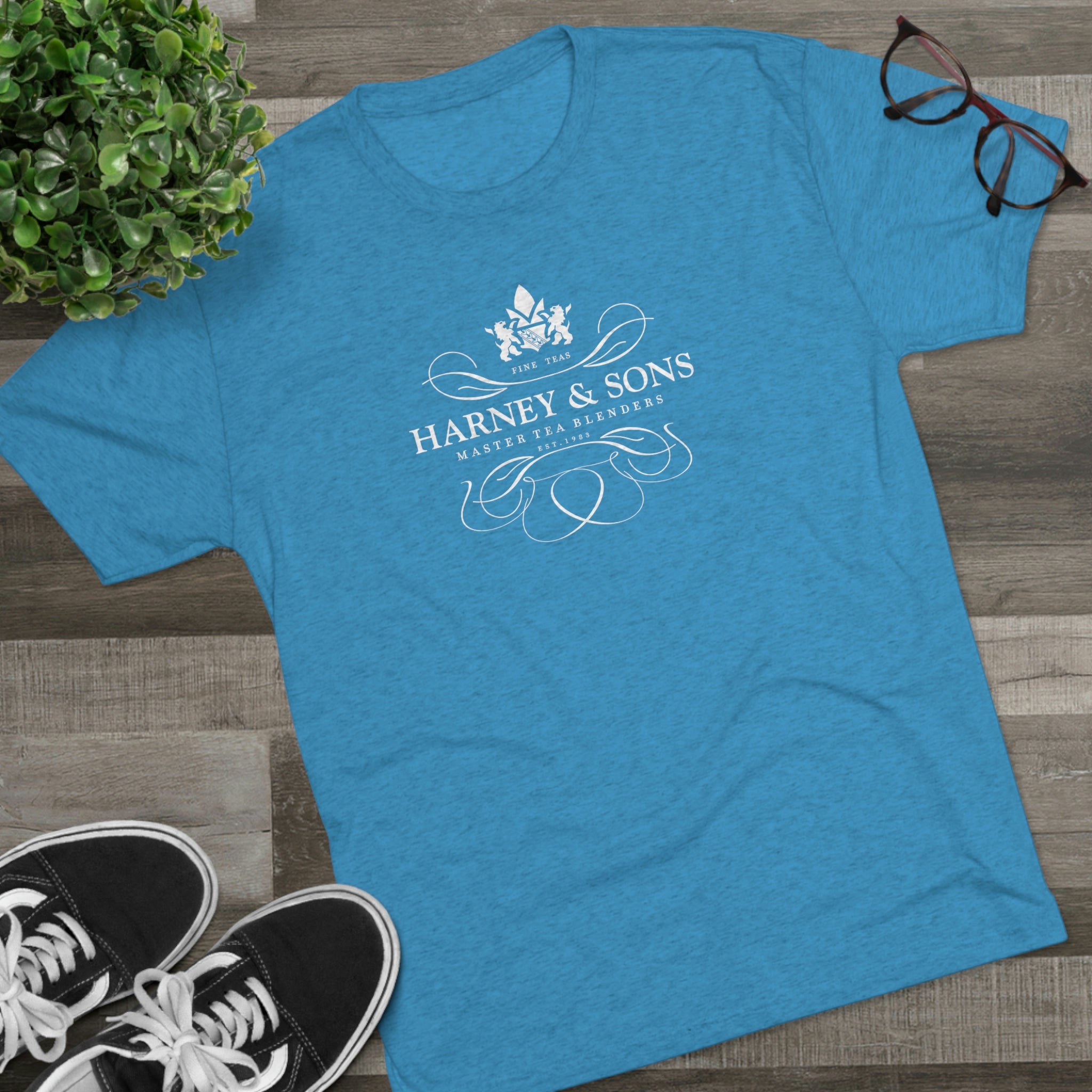 Blue graphic tee featuring the Harney & Sons logo, styled with a floral design and elegant typography.