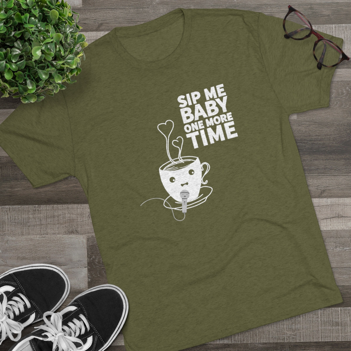 Olive green graphic tee featuring a playful coffee cup design with the text "Sip Me Baby One More Time.