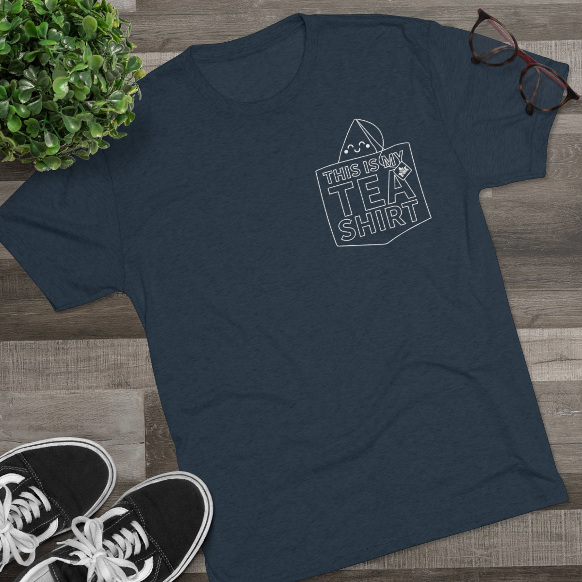 Navy graphic tee with "This Is My Tea Shirt" design, paired with sneakers and glasses on a wooden surface.