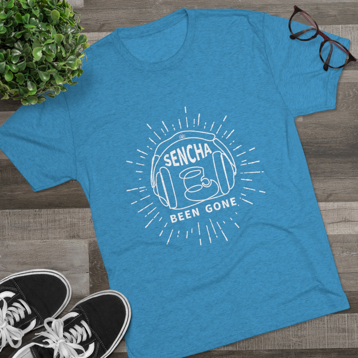 Blue graphic tee featuring "Sencha Been Gone" design with a tea cup and sunburst elements, styled with sneakers and glasses.