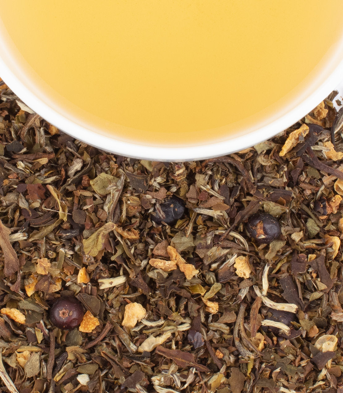 A close-up of loose herbal tea leaves with a cup of brewed tea above, showcasing earthy tones and citrus peels.