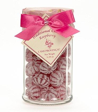 Glass jar filled with L'Ami Provençal traditional raspberry candy, tied with a pink ribbon.