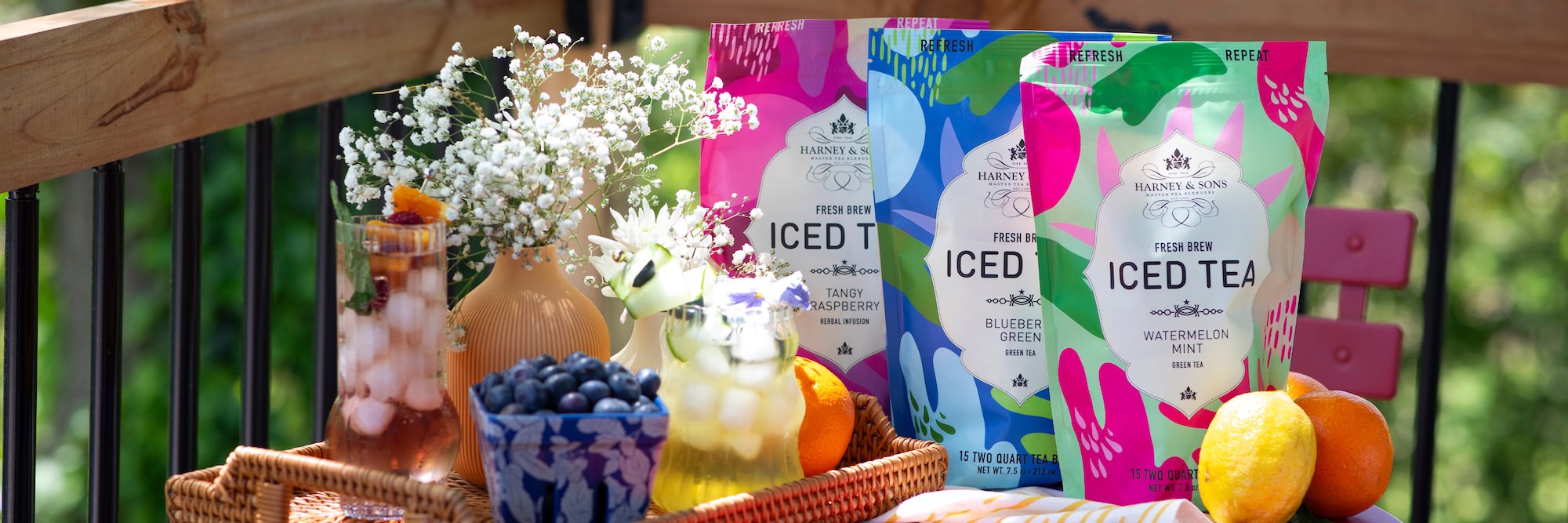 Three colorful packages of iced tea with glasses of iced tea with a garden backdrop.