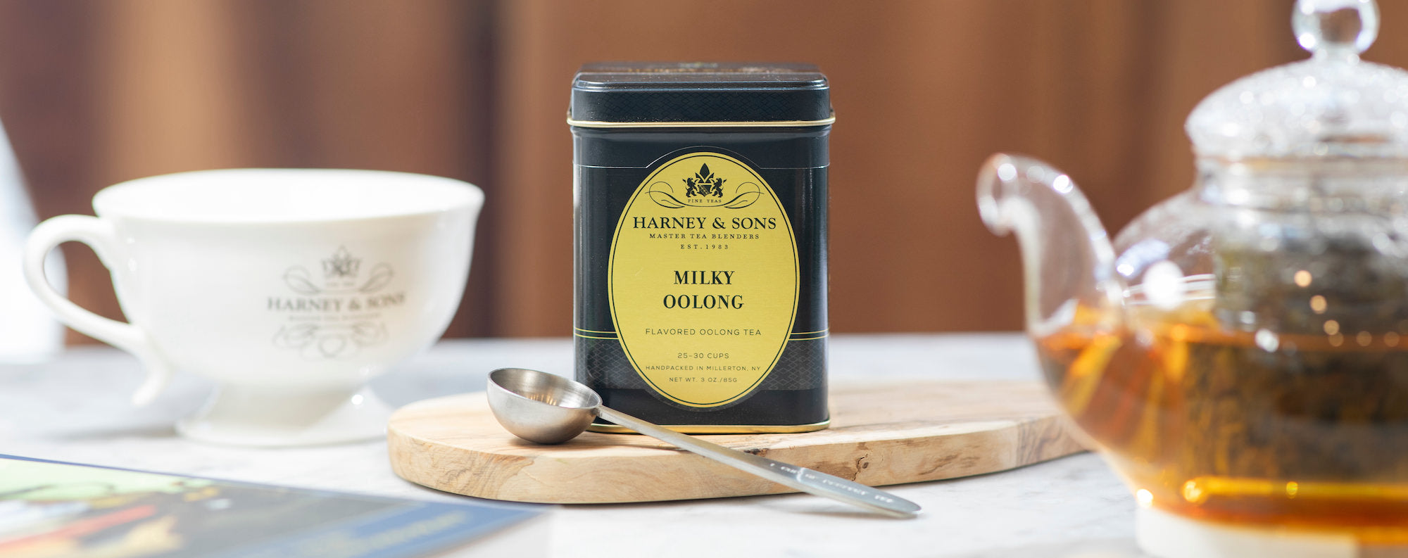 Harney & Sons Milky Oolong tea tin on a table with a teacup and teapot.