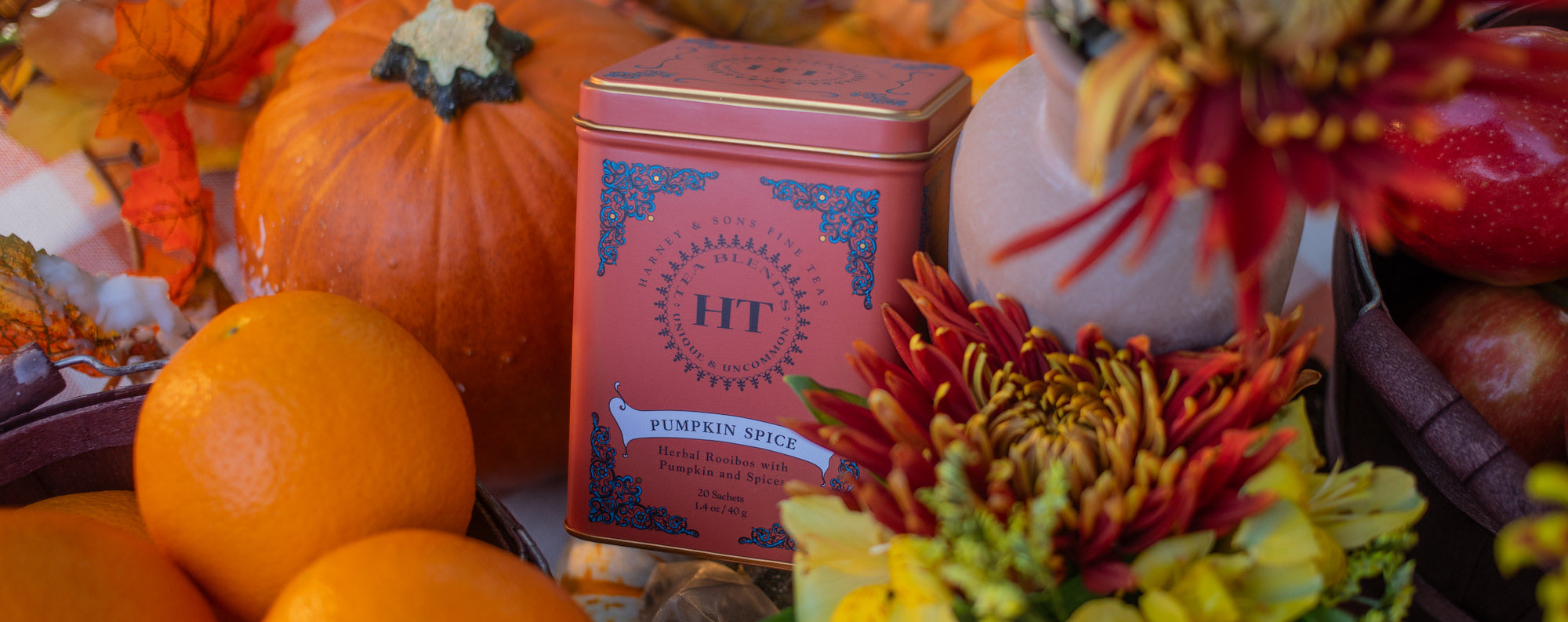 Pumpkin Spice tea tin with pumpkins, oranges, and flowers on a checkered table cloth.