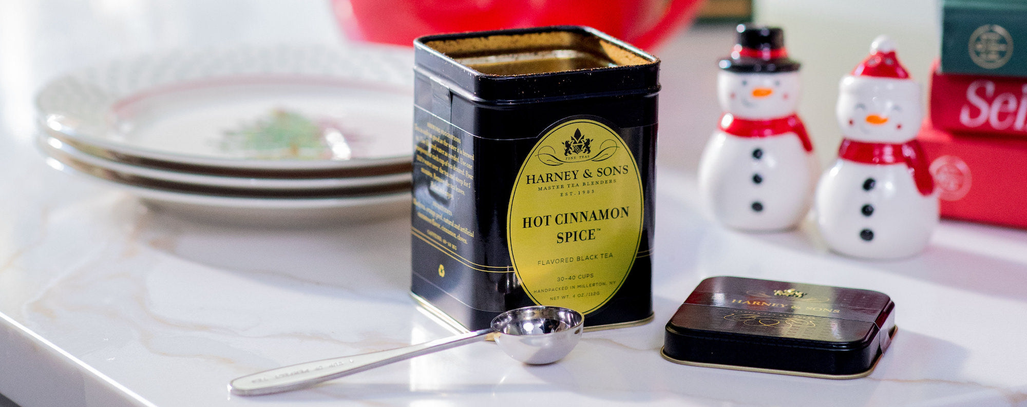 Harney & Sons hot cinnamon spice tin on a kitchen counter with a festive background.