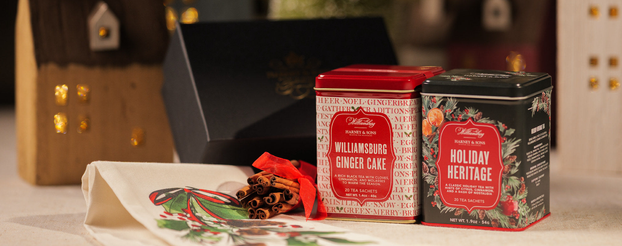 Two holiday-themed tea tins on a table with decorative items.
