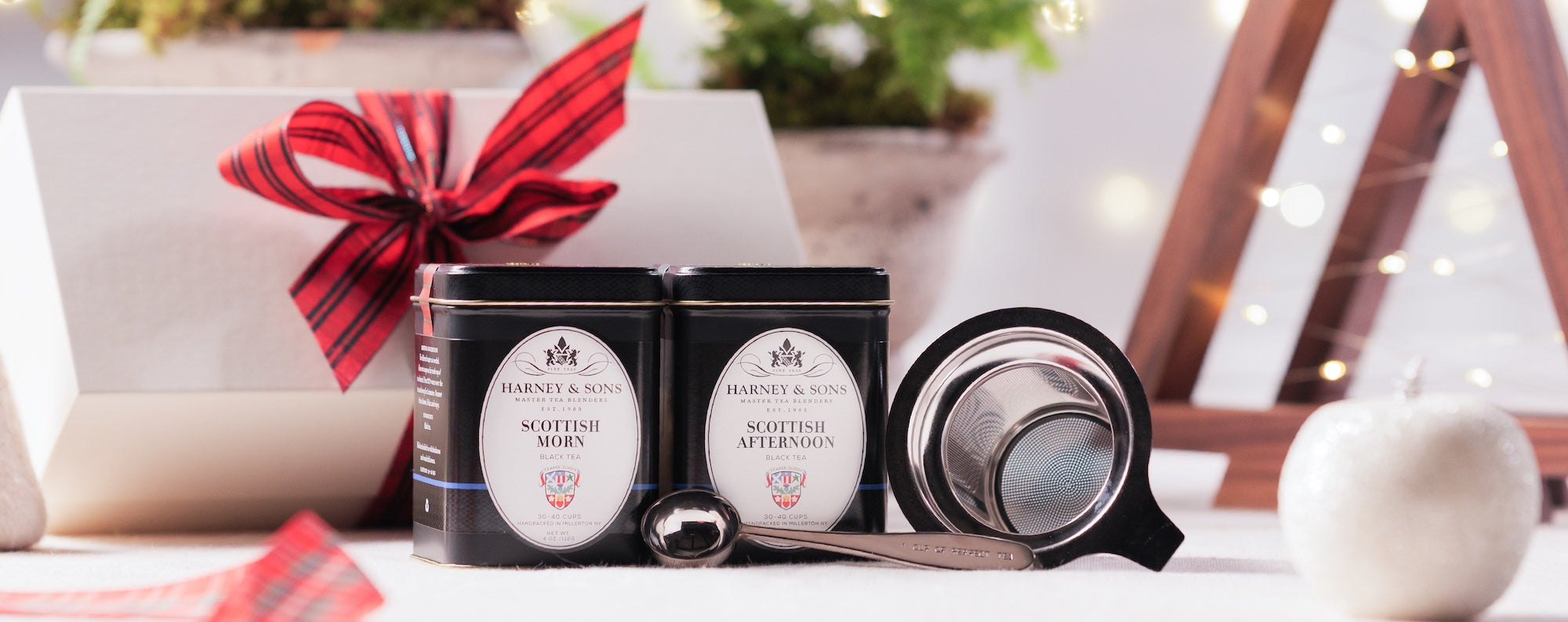 Scottish Morn and Scottish Afternoon tea tins with a tea infuser and tea spoon on a holiday themed table. 
