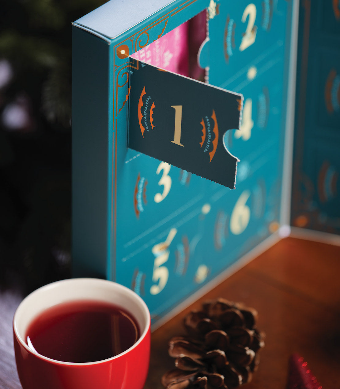 "Close-up of a 12 Days of Tea Winter Countdown advent calendar with a cup of tea and pinecone.