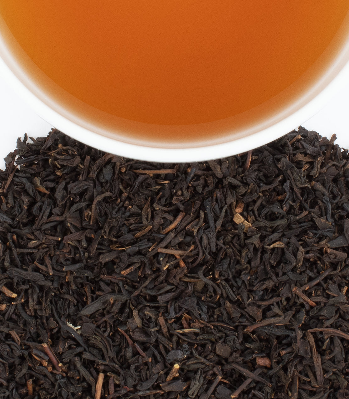 Hallowe'en Party tea with brewed tea in a cup and loose black tea leaves on a white background.